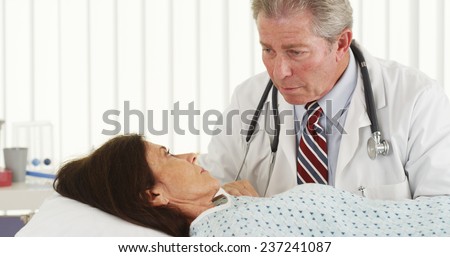 Mature doctor listening to elderly patient\'s heart