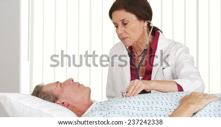 Senior doctor listening to mature patient\'s heart