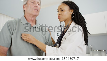 Black woman doctor listening to senior breathing