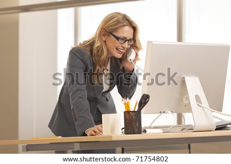Close-up of young businesswoman on the phone while looking at computer