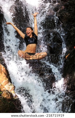 Carefree Woman enjoying in falling water with arms raised