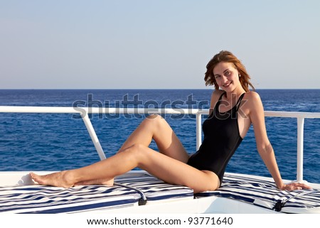 Young woman in bikini posing on yacht at sunny day