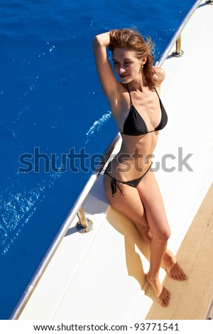 Young woman in bikini standing on yacht at sunny day