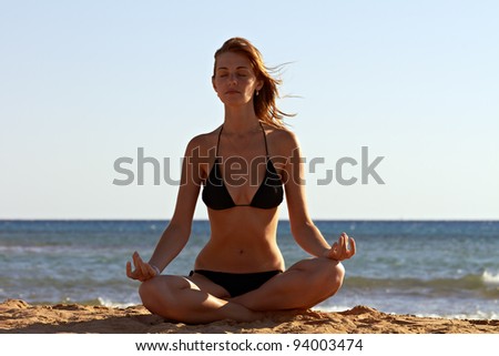 Silhouette of woman in yoga lotus meditation position back to seaside