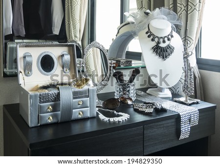 Beauty and make-up concept: table mirror,sunglasses,jewelry and makeup brushes on a black table