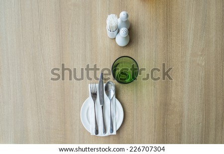 top view of table setting with glass and plate in restaurant - wood background