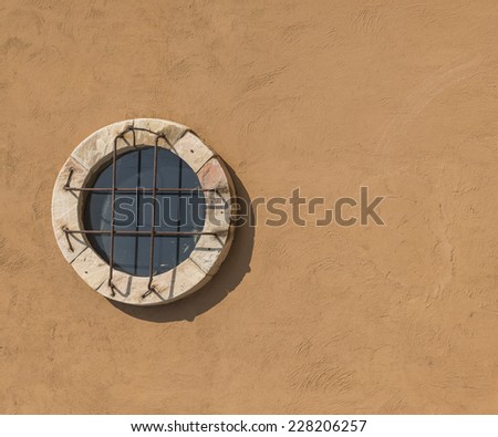 Old antique round window in rough plaster wall