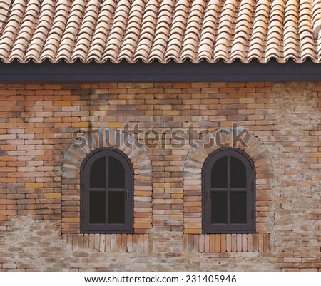 dark brown painted wood arched window in a red brick wall