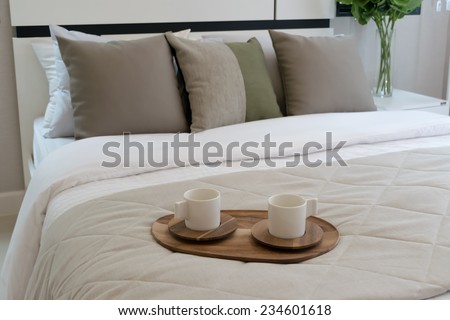 Decorative wooden tray with tea set on bed
