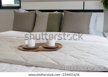 Decorative wooden tray with tea set on bed