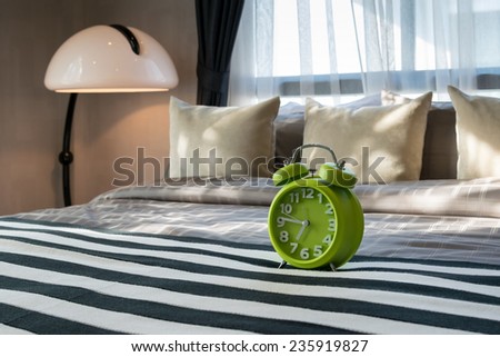 modern bedroom with green alarm clock on bed