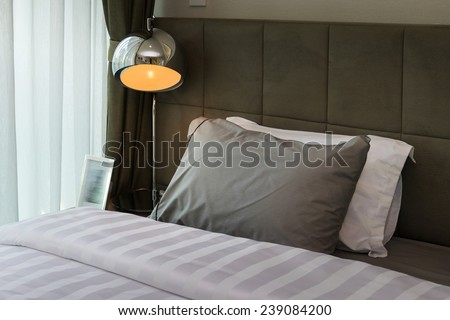 metal desk lamp and grey pillow on bed