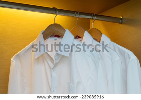 row of shirts hanging on coat hanger in wooden wardrobe