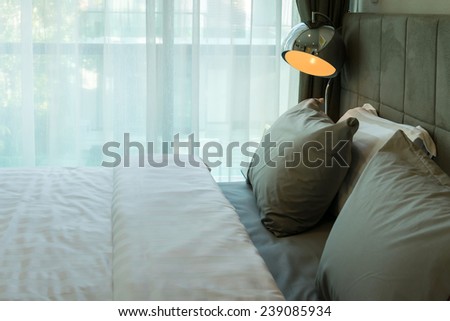 metal desk lamp and grey pillow on bed
