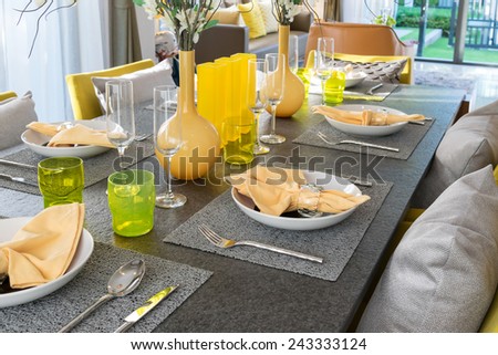 dining table and comfortable yellow chairs in modern home with elegant table setting
