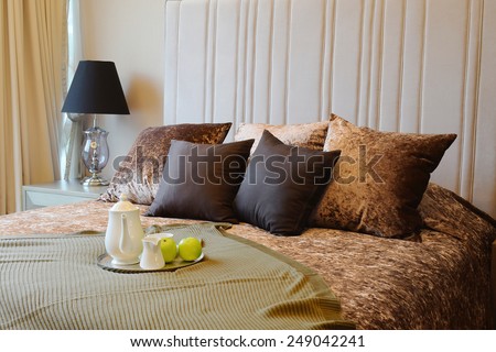 Decorative tray with tea set and green apple on the bed for breakfast.