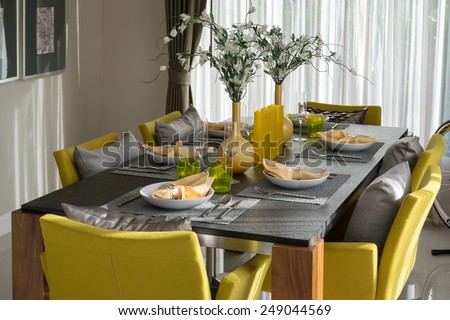 dining table and comfortable yellow chairs in modern home with elegant table setting