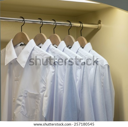 row of white shirts hanging on coat hanger in wardrobe