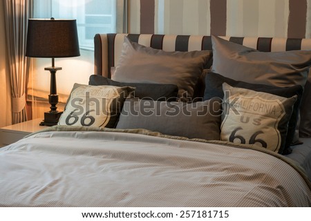 cozy bedroom interior with dark brown pillows and reading lamp on bedside table