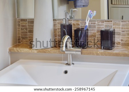 washbasin with faucet ,toothbrush and liquid soap bottle at home