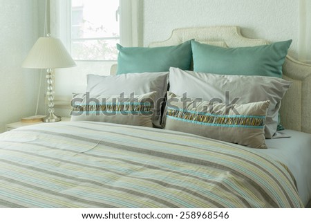 cozy bedroom interior with green pillows and reading lamp on bedside table