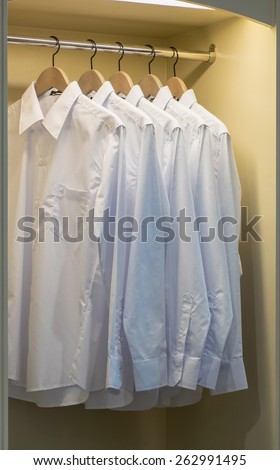 row of white shirts hanging on coat hanger in wardrobe
