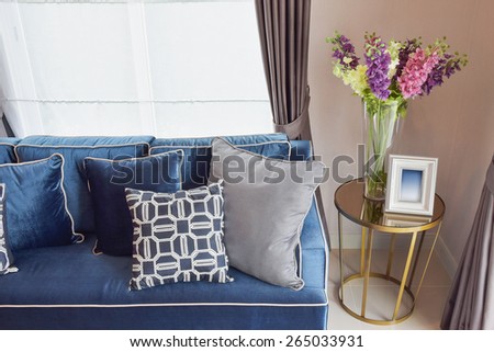 Navy blue classic sofa and retro pillows with a lovely orchid vase on side table in living corner
