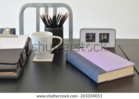 work table with book,pencils, cup of coffe and clock in a home