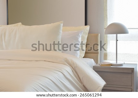 Cozy bedroom interior with pillows and reading lamp on bedside table