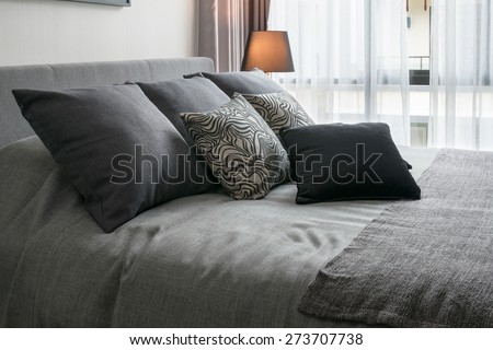 stylish bedroom interior design with black patterned pillows on bed and decorative table lamp.
