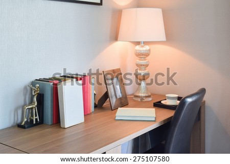 wooden table with reading lamp and books in modern working room interior