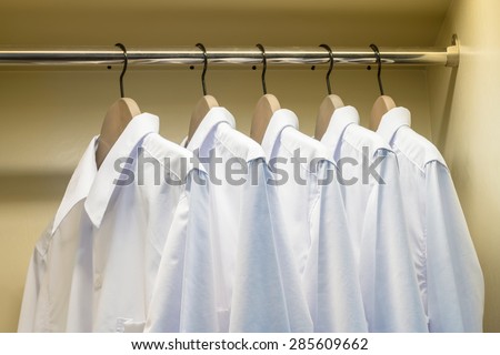 close up of white shirts hanging on coat hanger in wardrobe