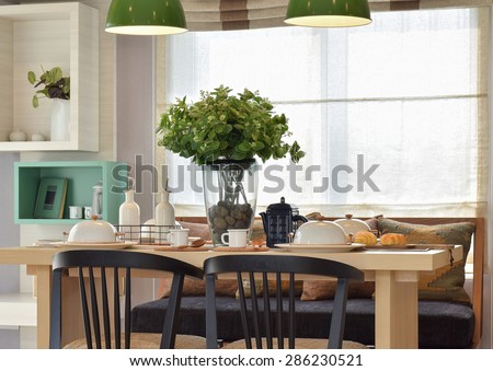 Breakfast setup on wooden table with nice vase and modern chair