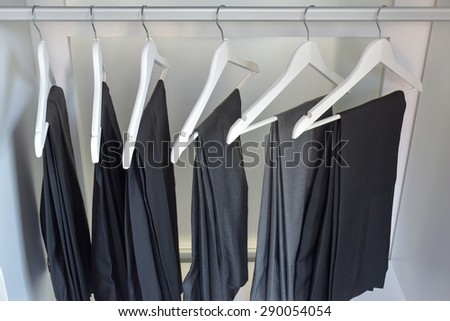 row of gray and black pants hangs in wardrobe at home