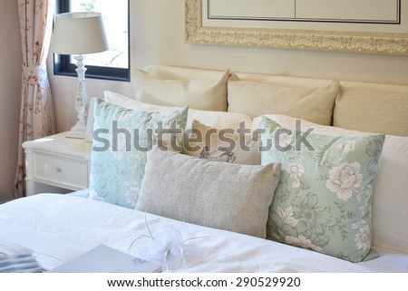vintage bedroom interior with flower pattern pillow and reading lamp on white bedside table