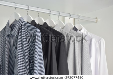 row of white, gray, black shirts hanging in wooden wardrobe
