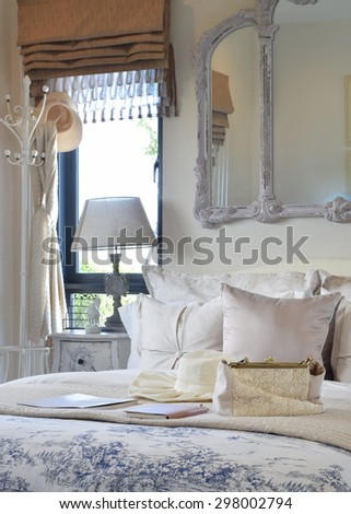 luxury bedroom interior with decorative set with vintage bag,hat,books on bed and classic style table lamp