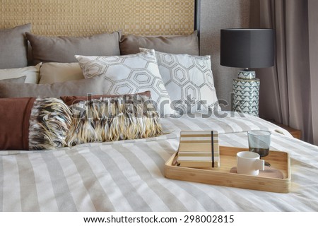 stylish bedroom interior with striped pillows and decorative tea set on bed