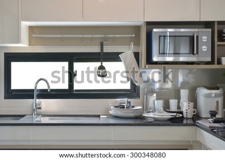 Ceramic ware and utensils setting up next to sink in modern kitchen