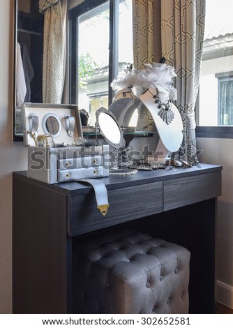 table mirror,sunglasses,jewelry and makeup brushes on a black dressing table