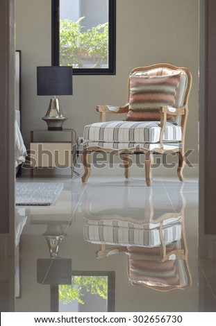 comfortable classic style lounge chair next to the bedside table in bedroom interior