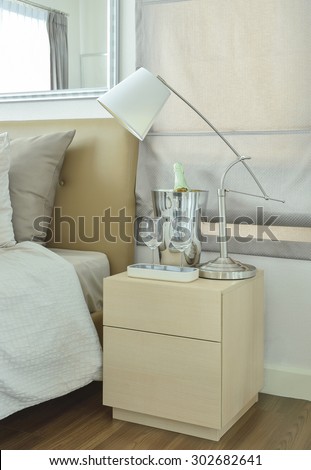 White table lamp with empty glasses and wine bottle on bed side table