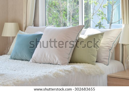 stylish bedroom interior design with colorful pillows on bed and decorative table lamp.