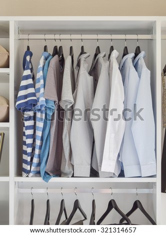 modern closet with row of shirts hanging in white wardrobe
