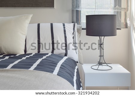 Ready lamp with black shade lamp on bedside table with striped pattern bedding