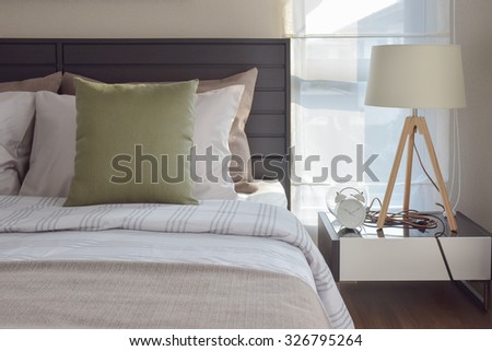 modern bedroom interior with green pillow and decorative wooden lamp on bedside table