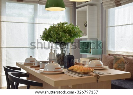 Breakfast setup on wooden table with nice vase and modern chair