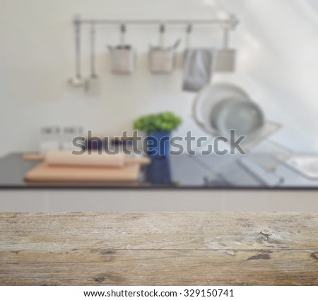 wooden table top with blur of modern ceramic kitchenware and utensils on the counter top
