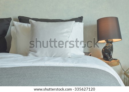 Clean bed in hotel guestroom with brown reading lamp