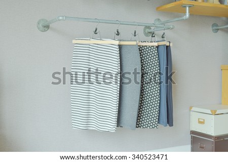 skirts hanging on industrial style clothes rail in walk in closet